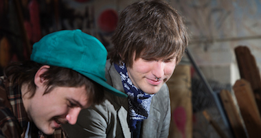 Smiling teen friends sitting in urban scene outdoors